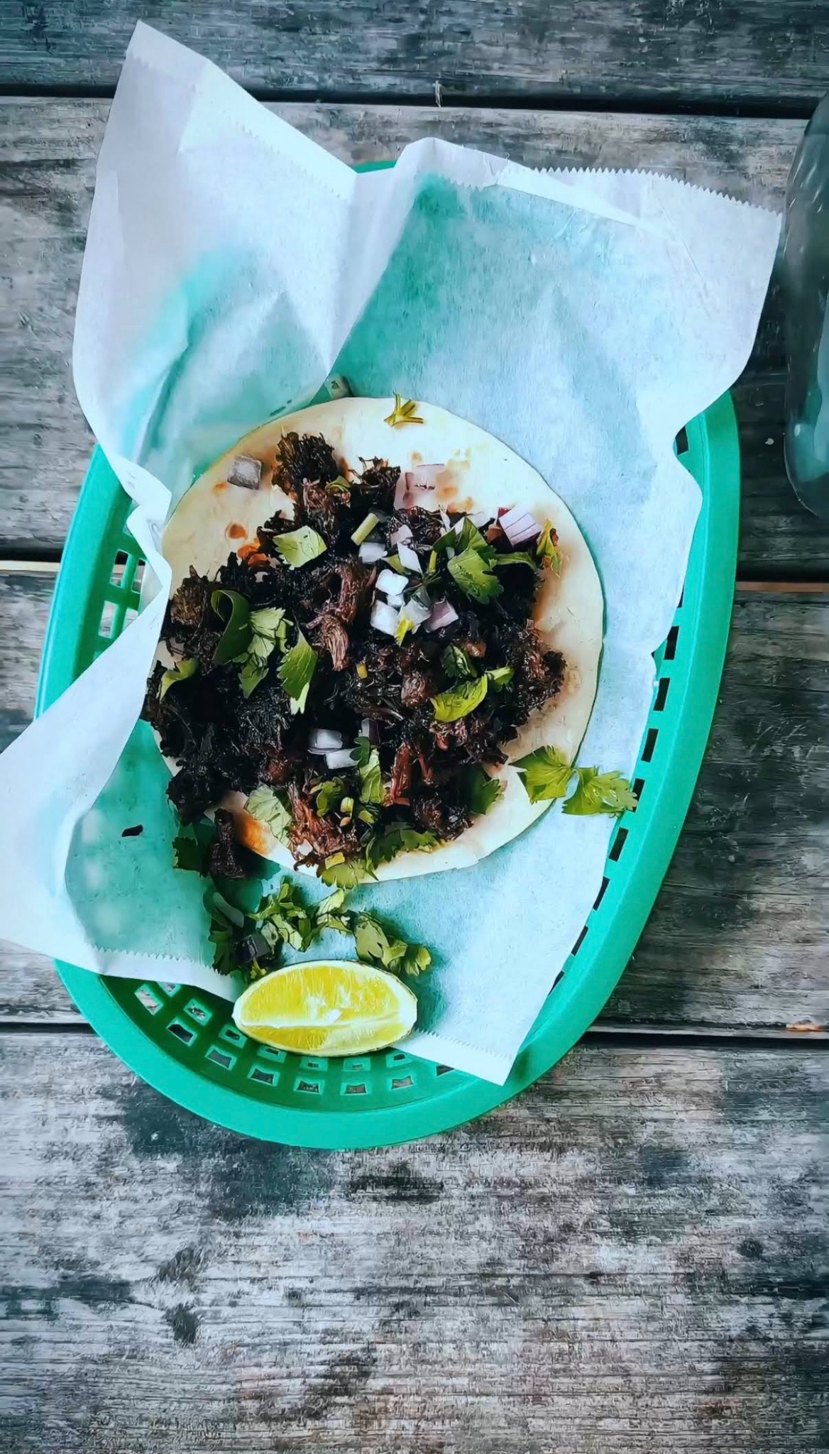 Barbacoa taco topped with cilantro and diced onion and served with lime