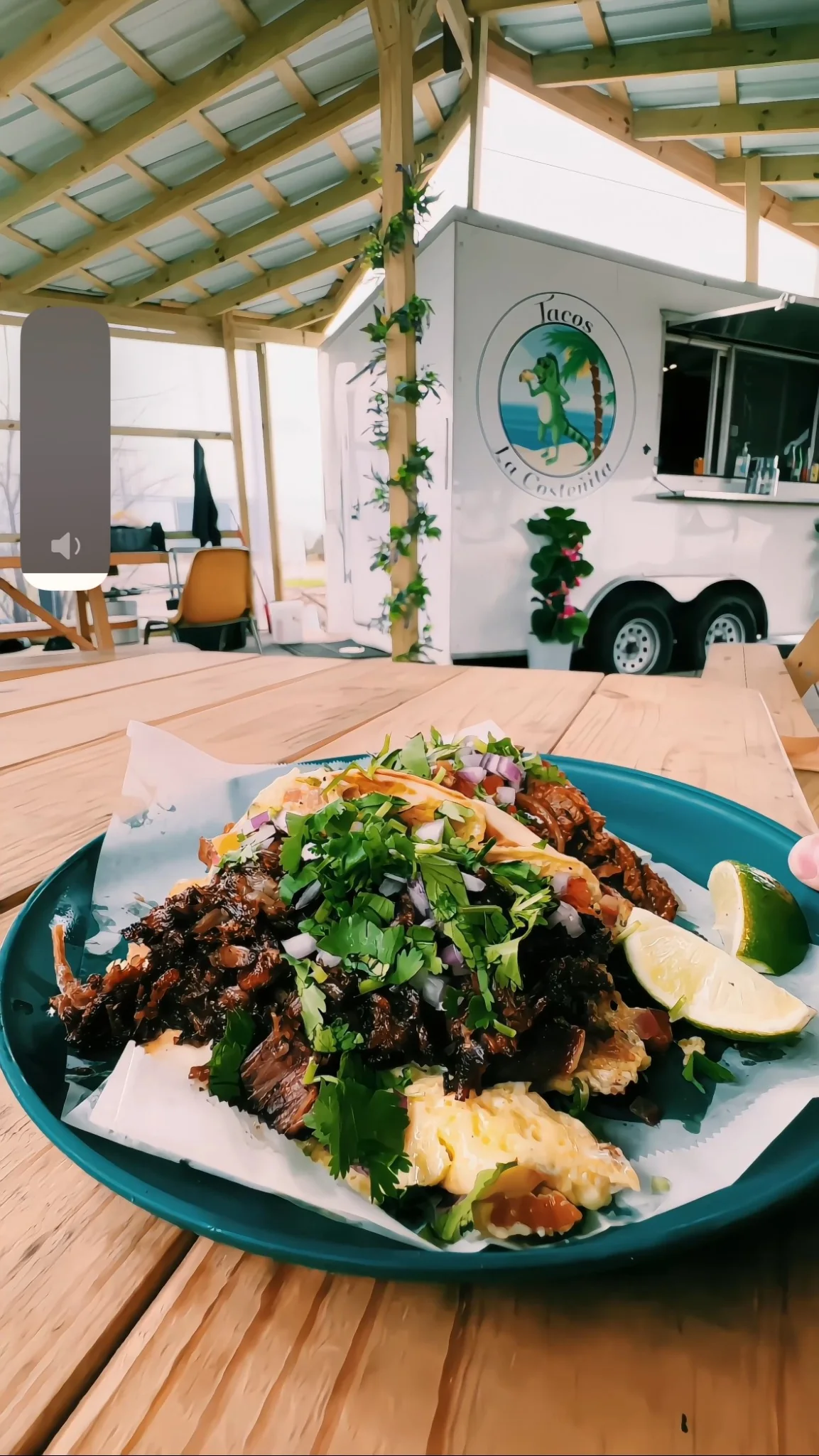 Taco plate on a wooden table in front of the Tacos La Costeñita truck