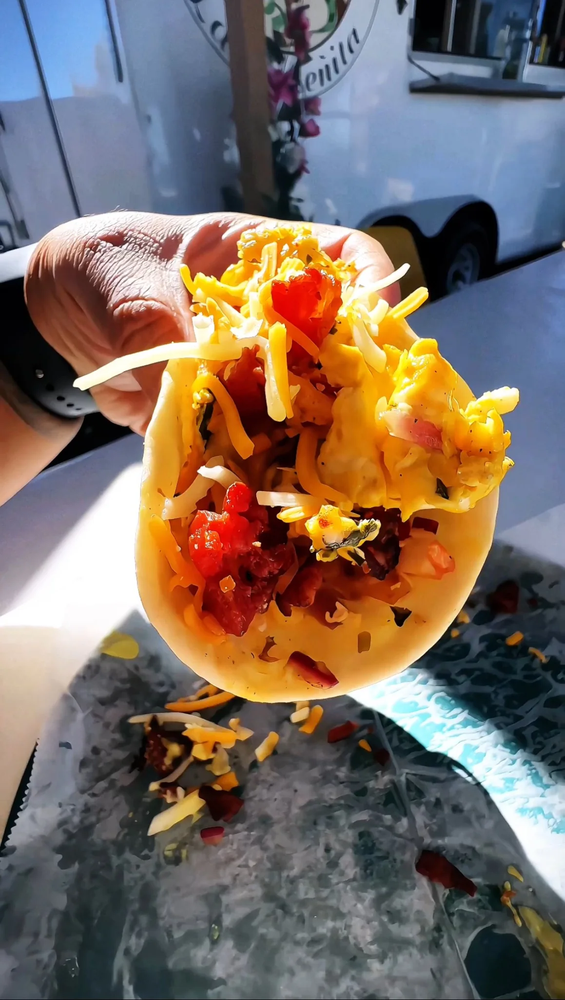 Hand holding a loaded breakfast taco outside the food truck