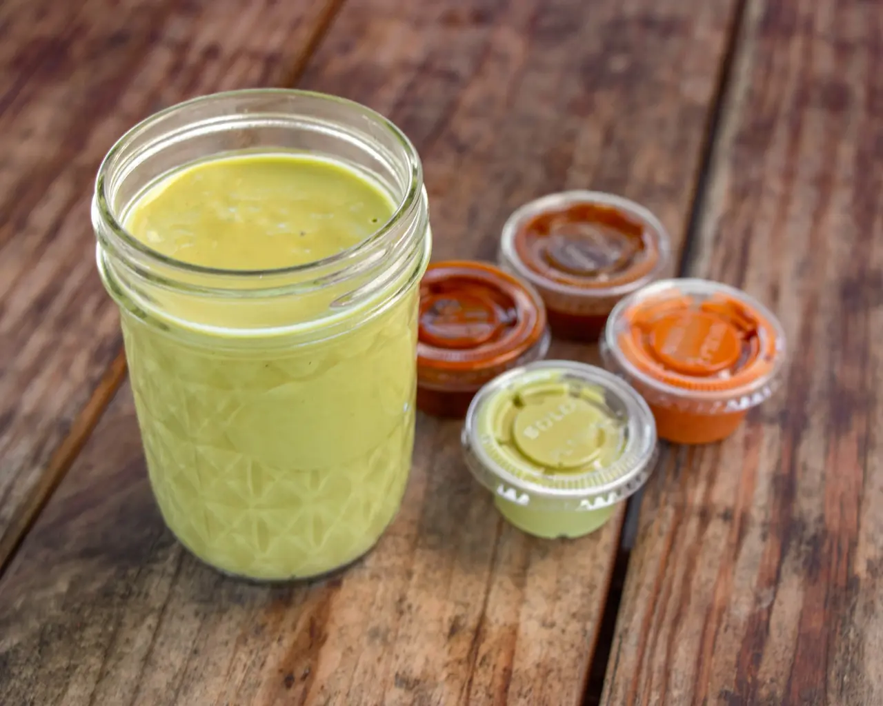 Jar of green house-made salsa with individual salsa cups.