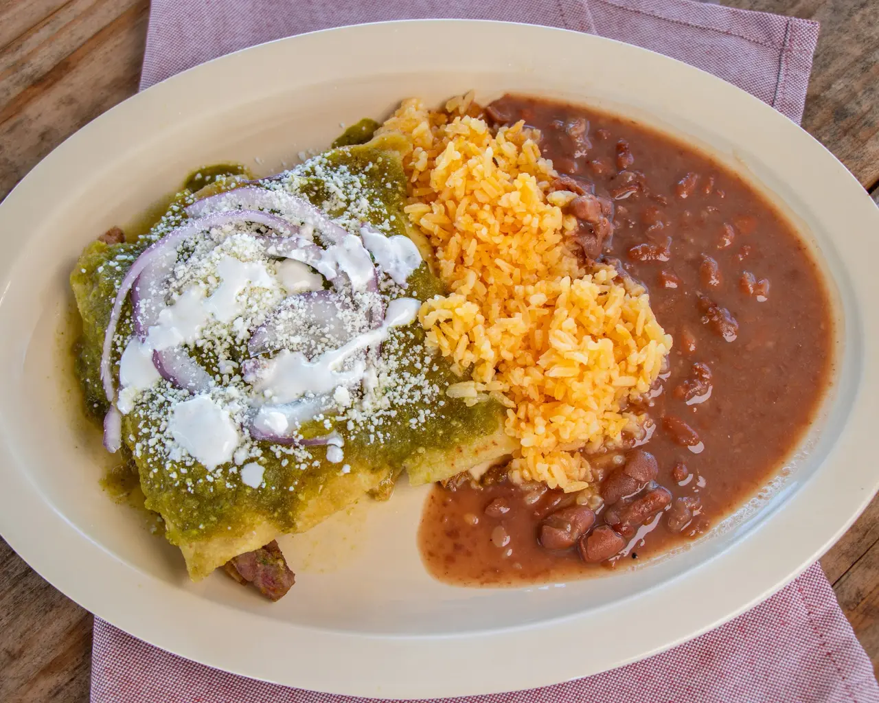 Plated Mexican meal with salsa verde, rice and beans.