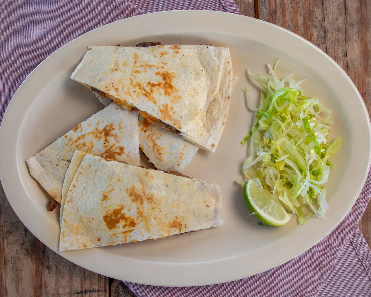 Griddled quesadilla wedges served with lettuce and lime.