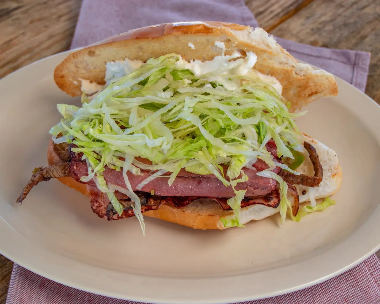 Torta Guerrero served on a toasted roll with meat, ham and lettuce.